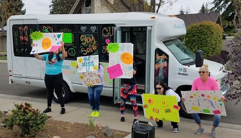 Manteca staff waving signs of encouragement in front of the house of an ABLE Consumer. Manteca staff waving signs of encouragement in front of the house of an ABLE Consumer.